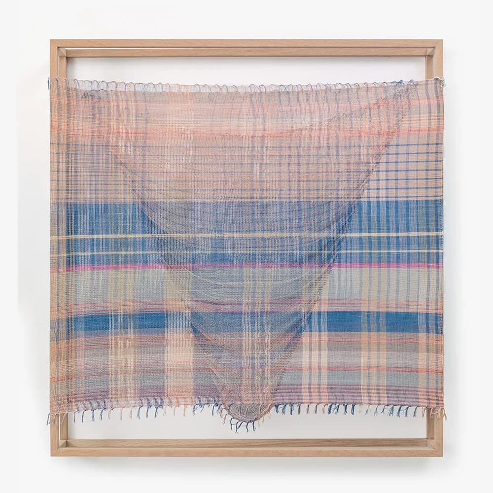 A minimalist room divider featuring a rectangular frame constructed from light-toned wood, supporting a semi-translucent woven textile panel. The textile exhibits a plaid pattern in shades of beige, blue, and pink, with finer lines in grey and darker blue. The fabric is draped over a single horizontal rod at the top and hangs loosely, revealing fringed edges at the bottom. The overall design emphasizes simplicity and texture. — 3D model
