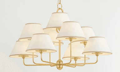 A contemporary or transitional chandelier featuring a satin brass finish and nine individual tapered fabric shades. The fixture is suspended by a chain and has multiple arms radiating outwards from a central hub, each supporting a light source covered by a cream-colored shade with subtle trim. — 3D model