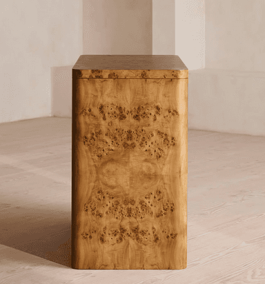 A three-drawer chest of drawers crafted with burl wood veneer, featuring rounded corners and edges, and circular recessed brass pull handles. The unit stands on integrated rounded feet. — 3D model