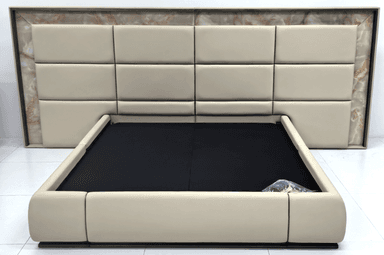 A modern platform bed featuring a generously padded, grid-patterned headboard integrated into a cream upholstered frame. The headboard is framed by a striking marble or stone-like trim. The platform base is also upholstered in cream, with a recessed black area indicating the mattress support. The overall aesthetic is one of contemporary luxury. — 3D model