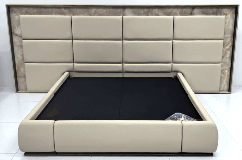 A modern platform bed featuring a generously padded, grid-patterned headboard integrated into a cream upholstered frame. The headboard is framed by a striking marble or stone-like trim. The platform base is also upholstered in cream, with a recessed black area indicating the mattress support. The overall aesthetic is one of contemporary luxury. — 3D model