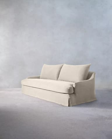 A light-colored, slipcovered two-seater loveseat with a casual aesthetic, featuring a skirted base and two separate seat and back cushions. The arms are gently sloped, and the overall appearance is soft and inviting. — 3D model