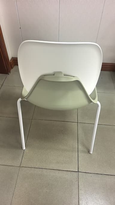 A modern side chair with a molded shell seat and back. The seat and back appear to be made of a smooth, durable plastic or composite material. The shell has a distinct organic, curved shape, with the back extending upwards and curving slightly inwards. The chair is supported by thin, tapered metal legs that are white in color and arranged in a sled-like base configuration. The overall aesthetic is minimalist and contemporary. — 3D model
