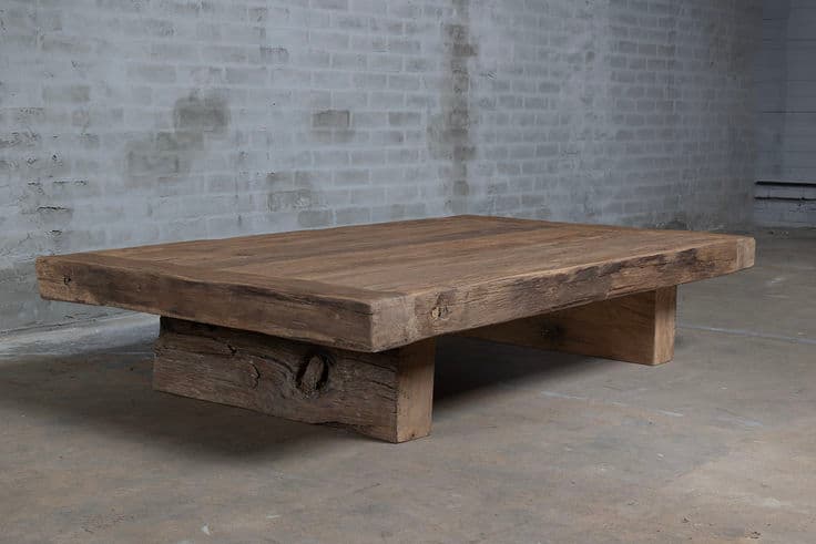 A rectangular, low-profile table constructed from reclaimed or distressed wood, featuring a thick, plank-style top and two sturdy, short support beams functioning as legs. The wood exhibits a natural, weathered grey-brown tone with visible grain and imperfections, contributing to a rustic aesthetic. — 3D model