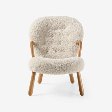 A contemporary lounge chair featuring a fully upholstered body in cream shearling fabric, with integrated curved wooden armrests and splayed wooden legs. — 3D model