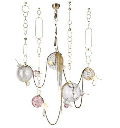 A striking multi-tiered chandelier featuring an intricate arrangement of brass-toned metalwork, decorative chains, and a variety of clear and pink glass spheres. Some glass elements are smooth, while others exhibit fluted or textured surfaces. The design includes cascading metal tassels and small, integrated light sources within or alongside the glass components, creating a luxurious and artistic statement piece. — 3D model