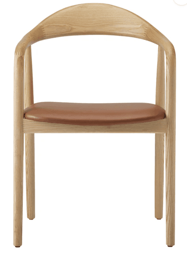 A Scandinavian modern armchair constructed from light-colored ash wood with a subtly visible grain. It features a continuous, gently curved element that forms both the backrest and the armrests, creating a fluid silhouette. The seat is a flat, padded cushion upholstered in a cognac-colored leather or faux leather. The frame is supported by four round, slightly tapered legs, connected by simple stretchers beneath the seat. — 3D model