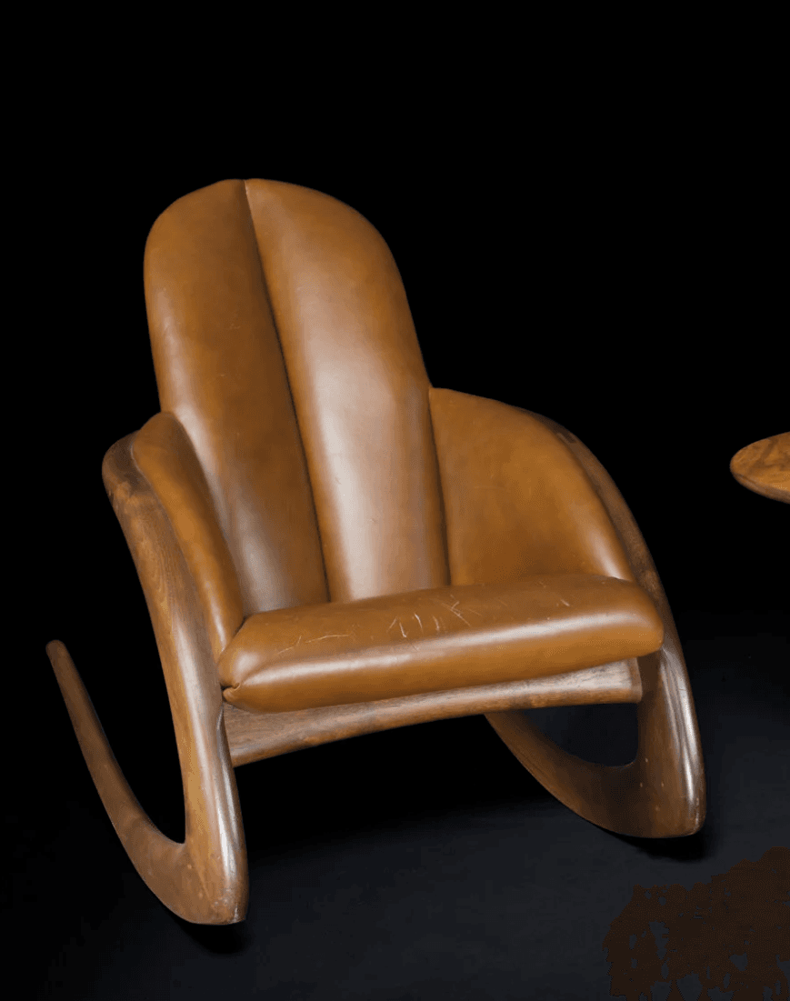A mid-century modern style rocking chair featuring a dark wood frame with elegant curved lines and rich brown leather upholstery on the seat, back, and armrests. The backrest is divided into two plush sections. — 3D model