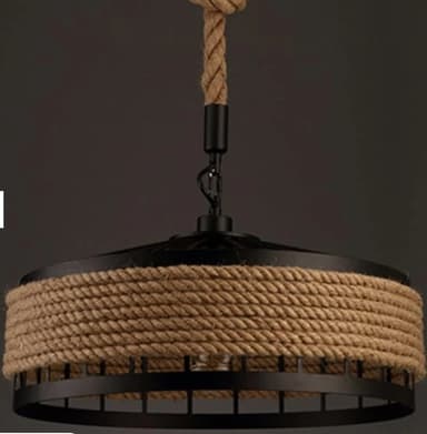A black metal and rope pendant light featuring a drum-shaped shade. The light is suspended by a thick, natural fiber rope that connects to a black circular ceiling canopy, with a decorative knot detail. The shade consists of a solid black metal top and a metal cage-like base, around which a substantial amount of natural rope is tightly wrapped, providing a rustic and textured aesthetic. — 3D model