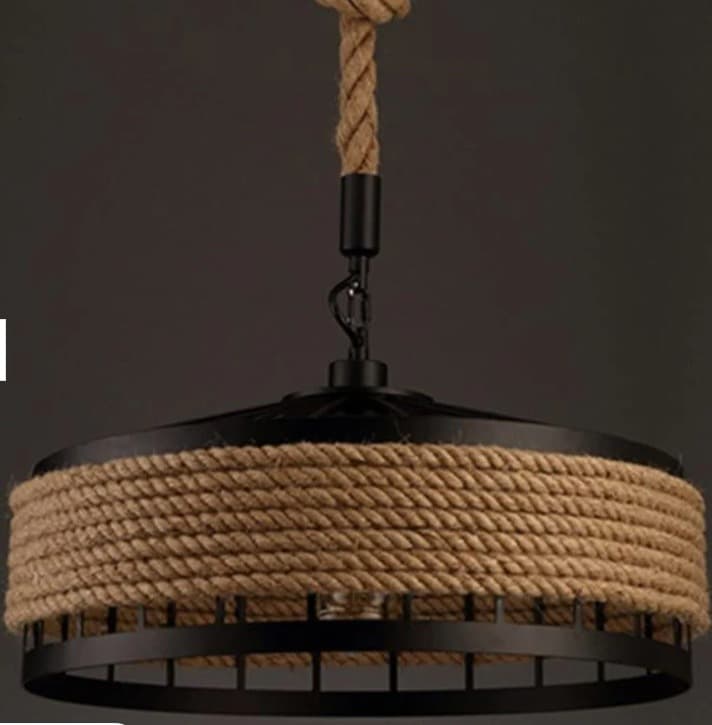 A black metal and rope pendant light featuring a drum-shaped shade. The light is suspended by a thick, natural fiber rope that connects to a black circular ceiling canopy, with a decorative knot detail. The shade consists of a solid black metal top and a metal cage-like base, around which a substantial amount of natural rope is tightly wrapped, providing a rustic and textured aesthetic. — 3D model