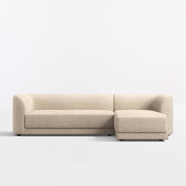 A sectional sofa with a chaise lounge attachment. The sofa features rounded armrests and a low profile design. It is upholstered in a textured fabric with a speckled pattern. The base is a dark, flat plinth or low legs. — 3D model