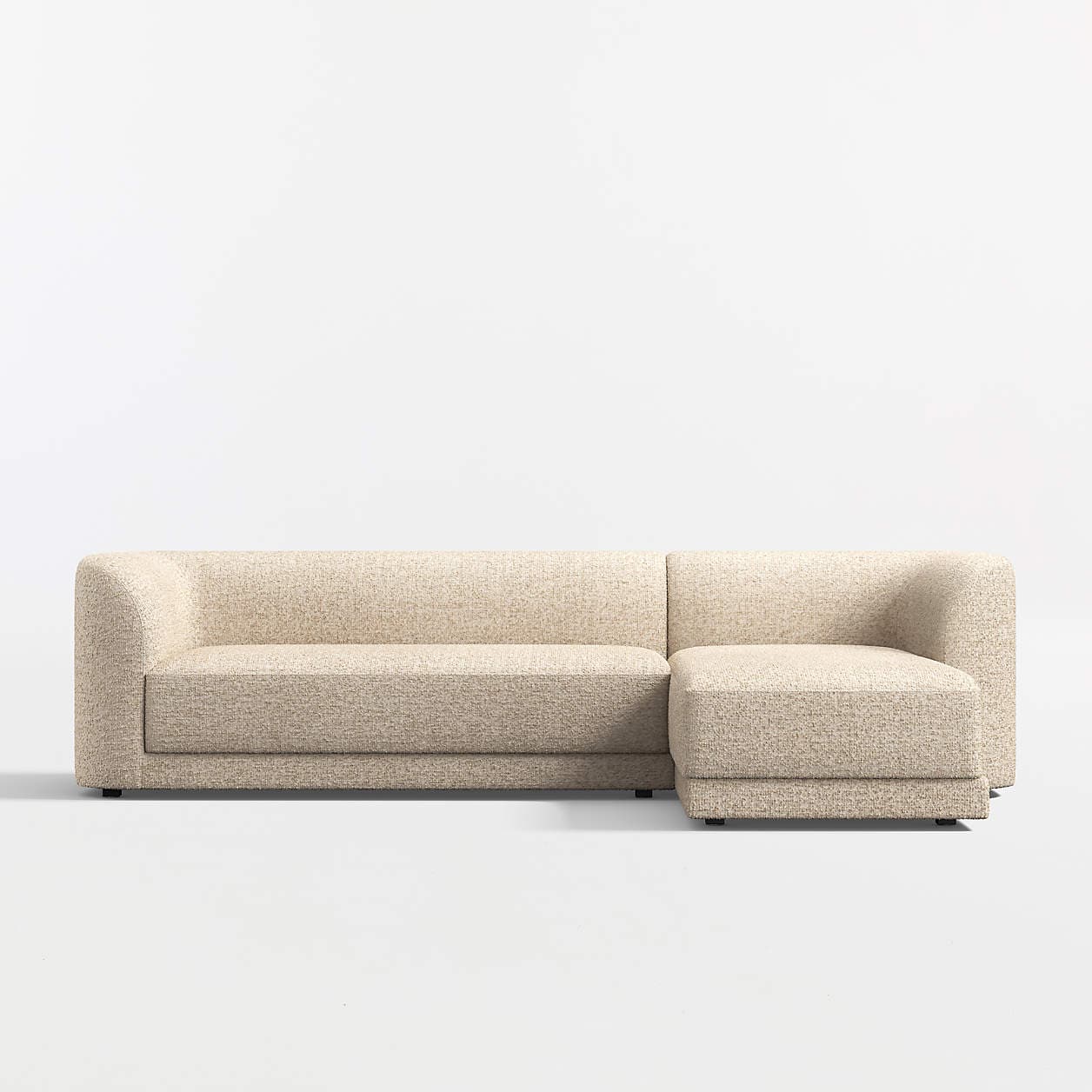 A sectional sofa with a chaise lounge attachment. The sofa features rounded armrests and a low profile design. It is upholstered in a textured fabric with a speckled pattern. The base is a dark, flat plinth or low legs. — 3D model
