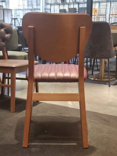 A modern dining chair constructed from a light brown wooden frame, featuring a distinctive rounded solid wood backrest and a channel-tufted upholstered seat in a reddish-brown (maroon) faux leather material. The chair's design emphasizes clean lines and a contemporary aesthetic, with the backrest appearing to be integrated seamlessly into the rear leg supports. — 3D model