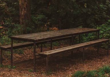 An outdoor picnic table with integrated benches, featuring a slatted dark wood tabletop and matching bench seats, all supported by a sturdy dark-colored metal frame with a minimalist, angular design. — 3D model