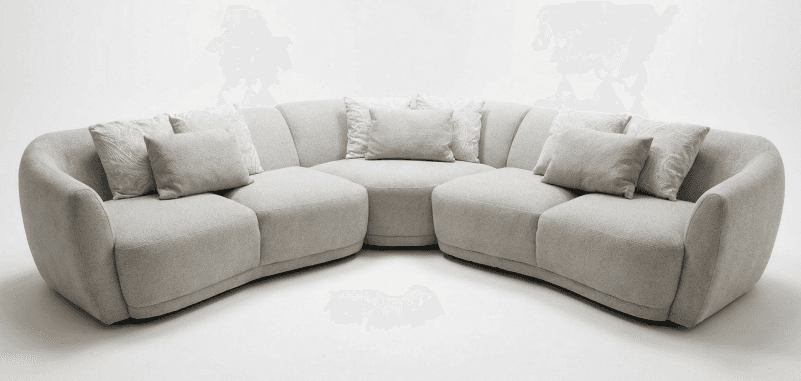 A large, modern modular sectional sofa upholstered in a light-colored, textured fabric. It features a curved design composed of multiple individual units that connect to form an expansive seating arrangement. The sofa has a low profile, rounded edges, and plush cushions, suggesting a focus on comfort and contemporary aesthetics. Several throw pillows, some matching the upholstery and others with a subtle pattern, are included. — 3D model