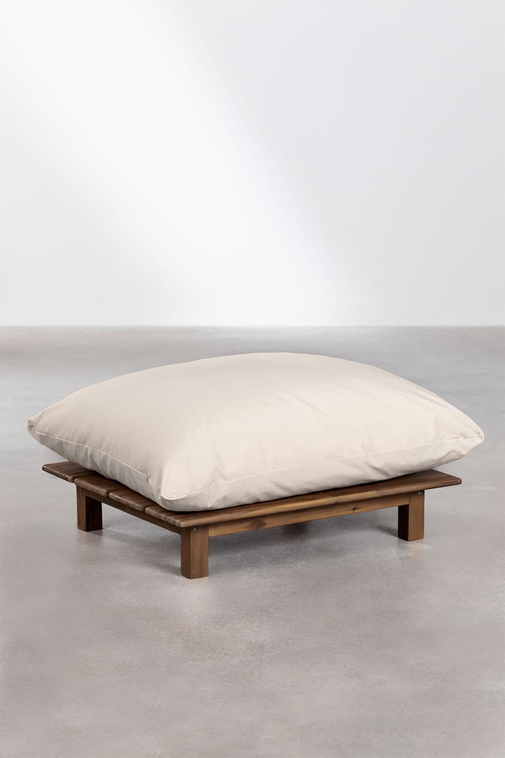 A low-profile ottoman with a wooden slatted base and a large, plush, cream-colored cushion. The base appears to be constructed from dark wood planks laid horizontally and supported by four short, block-style legs. The cushion is generously filled and contours to the base, suggesting a comfortable, oversized design. The overall aesthetic leans towards a relaxed, possibly outdoor or bohemian style. — 3D model