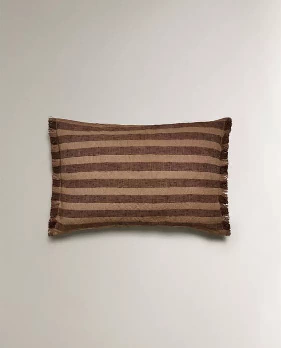 A rectangular pillow with a striped pattern. The stripes alternate between a lighter beige and a darker brown. The fabric appears to have a textured finish, possibly a woven material. The edges of the pillow have a decorative fringe detail. — 3D model