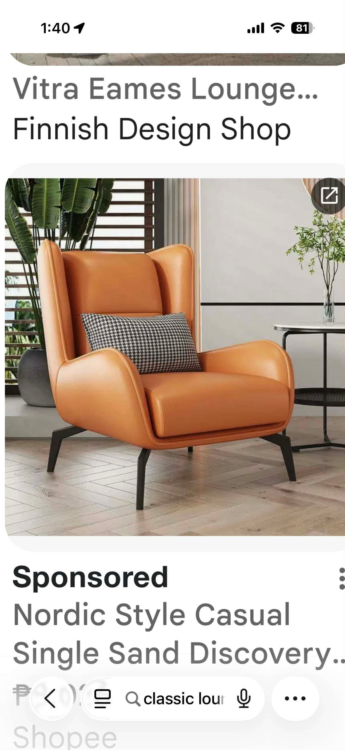 A contemporary armchair with a high back and winged sides, upholstered in tan-colored leather. It features a small, checkered throw pillow placed on the seat. The armchair is supported by four slender, black metal legs with an angular design. — 3D model