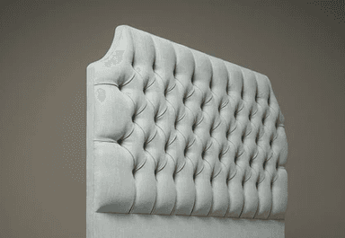 A light blue upholstered headboard with a tufted design. The tufting creates a diamond pattern with buttons at each intersection. The headboard has a slightly arched top and is mounted on a base that is not fully visible. — 3D model
