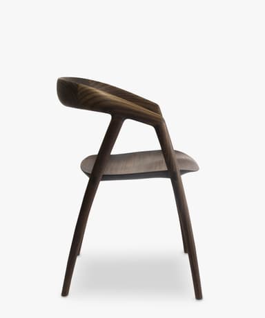 A contemporary armless chair crafted from dark walnut wood, featuring a curved backrest and a subtly sculpted seat, supported by four slender, round legs. — 3D model