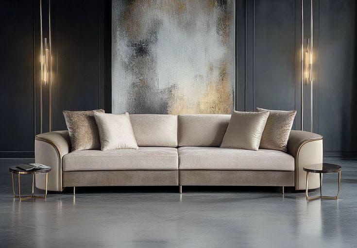A modern two-piece sectional sofa featuring a modular design with rounded arms and a two-tone upholstery scheme. The main seating and back cushions are a light beige fabric, while the base and outer arm sections are a slightly darker brown fabric or faux leather, accented by a lighter piping detail. Several decorative throw pillows in coordinating colors and textures are included. The sofa rests on short, discreet gold-finished metal legs. — 3D model