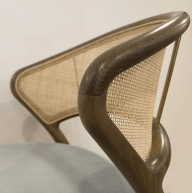 A dining chair with a curved wooden frame and a woven cane backrest. The seat is upholstered in a light grey fabric. The legs are tapered wooden spindles. — 3D model