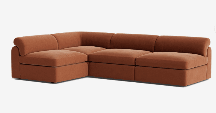 A modular sectional sofa featuring a low profile with deep seats and plush cushions. The sofa has a contemporary design with rounded arms and backrests. It appears to be upholstered in a soft, textured fabric. — 3D model