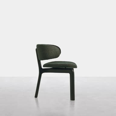 A modern armless chair featuring a low, plush, dark green bouclé-textured upholstered backrest and seat, separated by a distinct gap. The chair is supported by a sturdy, dark, minimalist H-shaped frame that also forms its four block-like legs. The design emphasizes clean lines and a compact footprint. — 3D model