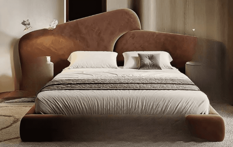 A contemporary upholstered bed frame with a distinctive, asymmetrical headboard. The headboard features two curved, wing-like panels of varying heights. The bed frame is low-profile and fully upholstered, including the side rails and footboard. It is presented with a mattress, two white pillows, and a grey quilted comforter. — 3D model