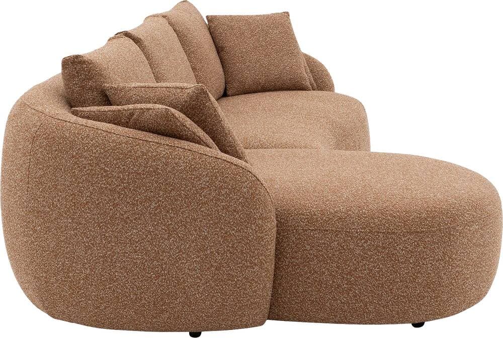 A modern, curved sectional sofa upholstered in a textured, light brown or tan boucle-style fabric. The sofa features a low-profile design with an integrated chaise lounge section on one side, offering ample seating and lounging space. Its backrest and armrests are gently rounded, providing a soft, organic aesthetic. Several loose back cushions are provided for comfort. — 3D model