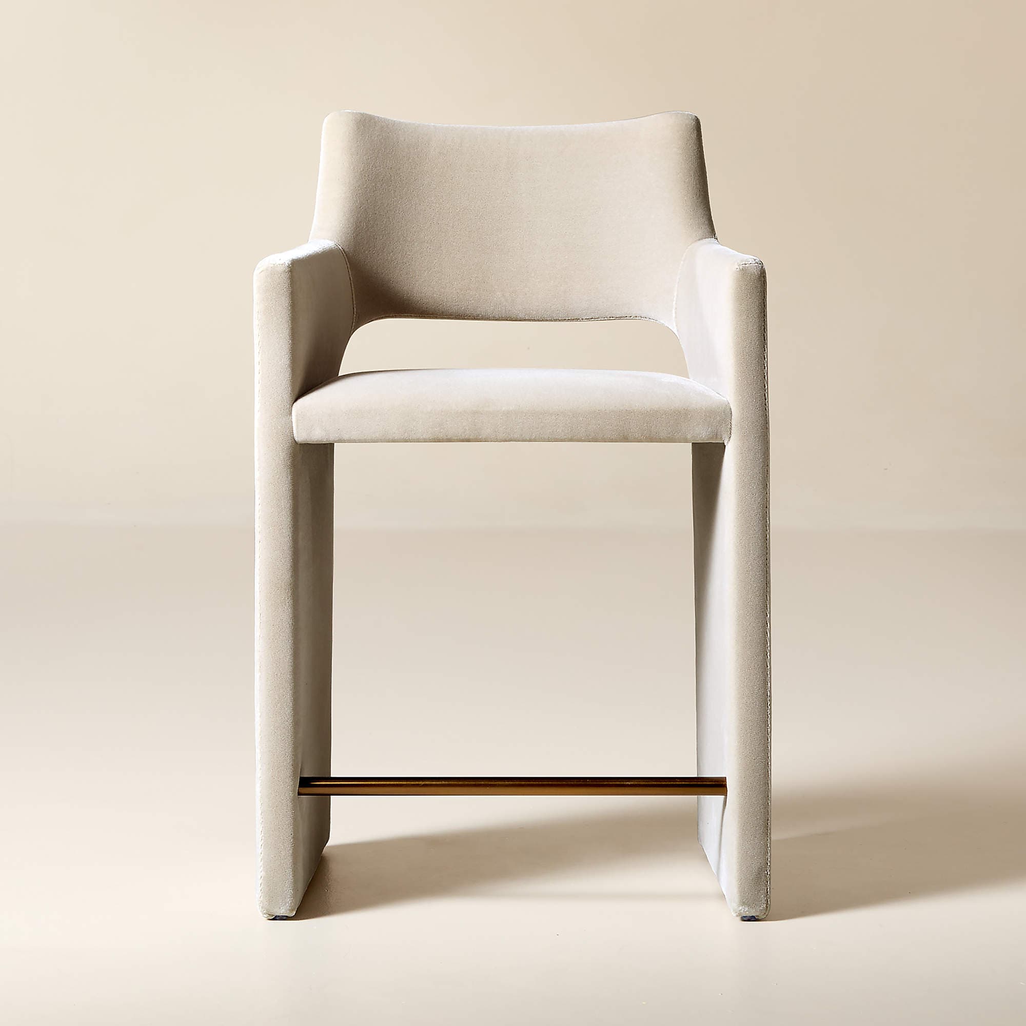 A contemporary bar stool with a sleek, minimalist design. It features a high back and armrests that are integrated into the main frame. The seat is upholstered, and the legs are substantial and straight. A metallic footrest spans between the two front legs, providing additional stability and functionality. — 3D model