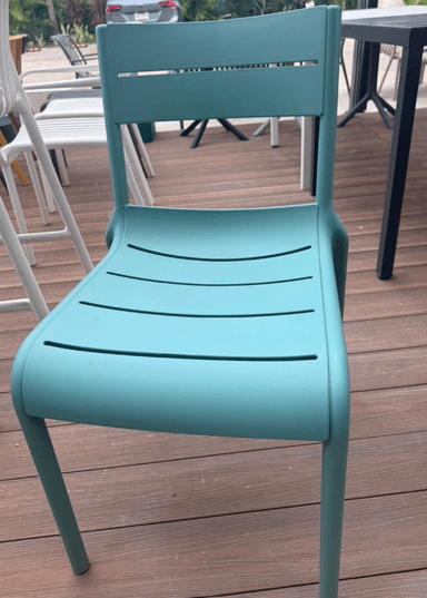 A modern, armless dining chair constructed from a single mold of teal-colored plastic, featuring a slat-back and slat-seat design. — 3D model
