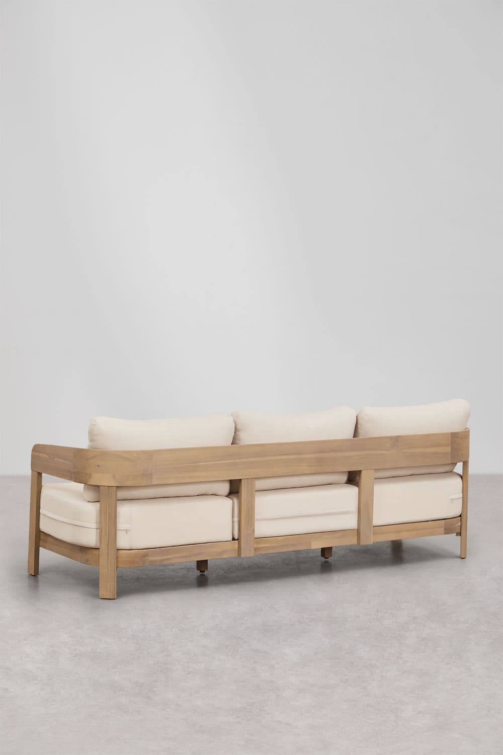 A three-seater sofa featuring a robust natural teak wood frame and three sets of light-colored, removable fabric cushions for the seat and back. The frame has a low profile with a continuous, rounded top rail forming the armrests and backrest, supported by vertical slats at the back. The sofa appears designed for outdoor or casual indoor use. — 3D model
