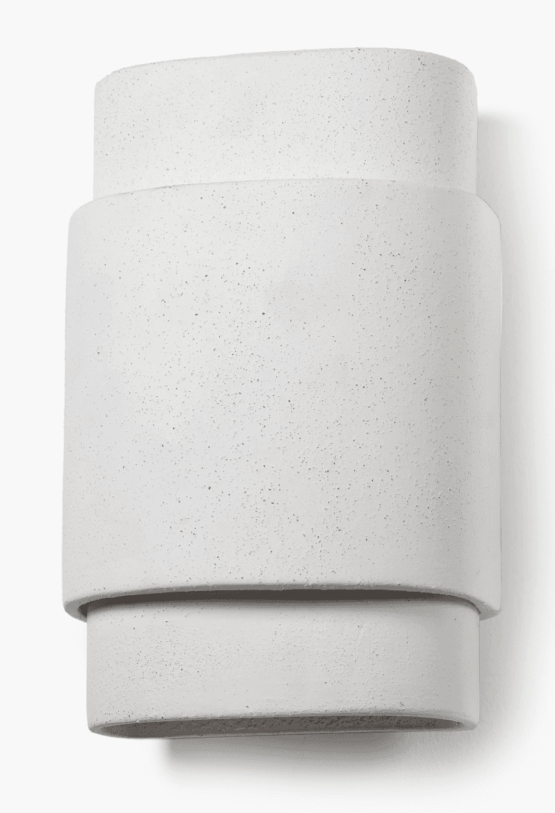 A minimalist wall-mounted lighting fixture, likely a sconce, featuring a stacked oval design. The object appears to be made from concrete or a similar textured, light-grey composite material. It consists of a larger central oval section, flanked by a slightly smaller, shallower oval section at the top and bottom, creating a layered, three-dimensional effect. The surfaces are uniformly textured with a speckled, raw concrete finish. The design suggests an upward and/or downward light projection, characteristic of modern architectural lighting. — 3D model