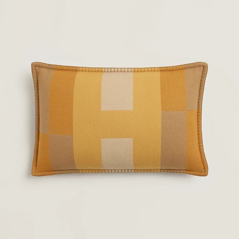 A rectangular decorative throw pillow featuring a geometric pattern composed of blocks of color in varying shades of yellow, beige, and light brown. The pillow has piped edges in a solid tan color, suggesting a finished, tailored look. The fabric appears to be a woven textile, possibly wool or a blend, with a visible texture. — 3D model