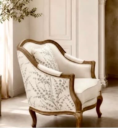 An elegant French Provincial style armchair featuring an exposed, dark stained wood frame with ornate carvings and curves. The chair is upholstered in an off-white or cream-colored fabric, with the outer back panel adorned with a subtle grey botanical or floral pattern. It has a plush seat cushion and padded armrests for comfort, supported by gracefully curved cabriole legs. — 3D model