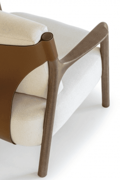 A modern upholstered lounge chair viewed from the back. It features a light-colored fabric on the seat and back cushions, supported by a dark wooden frame. A broad, saddle-brown leather or faux leather strap forms the outer backrest, wrapping around the wooden uprights and secured with visible stitching. The chair appears to be well-constructed with clean lines. — 3D model