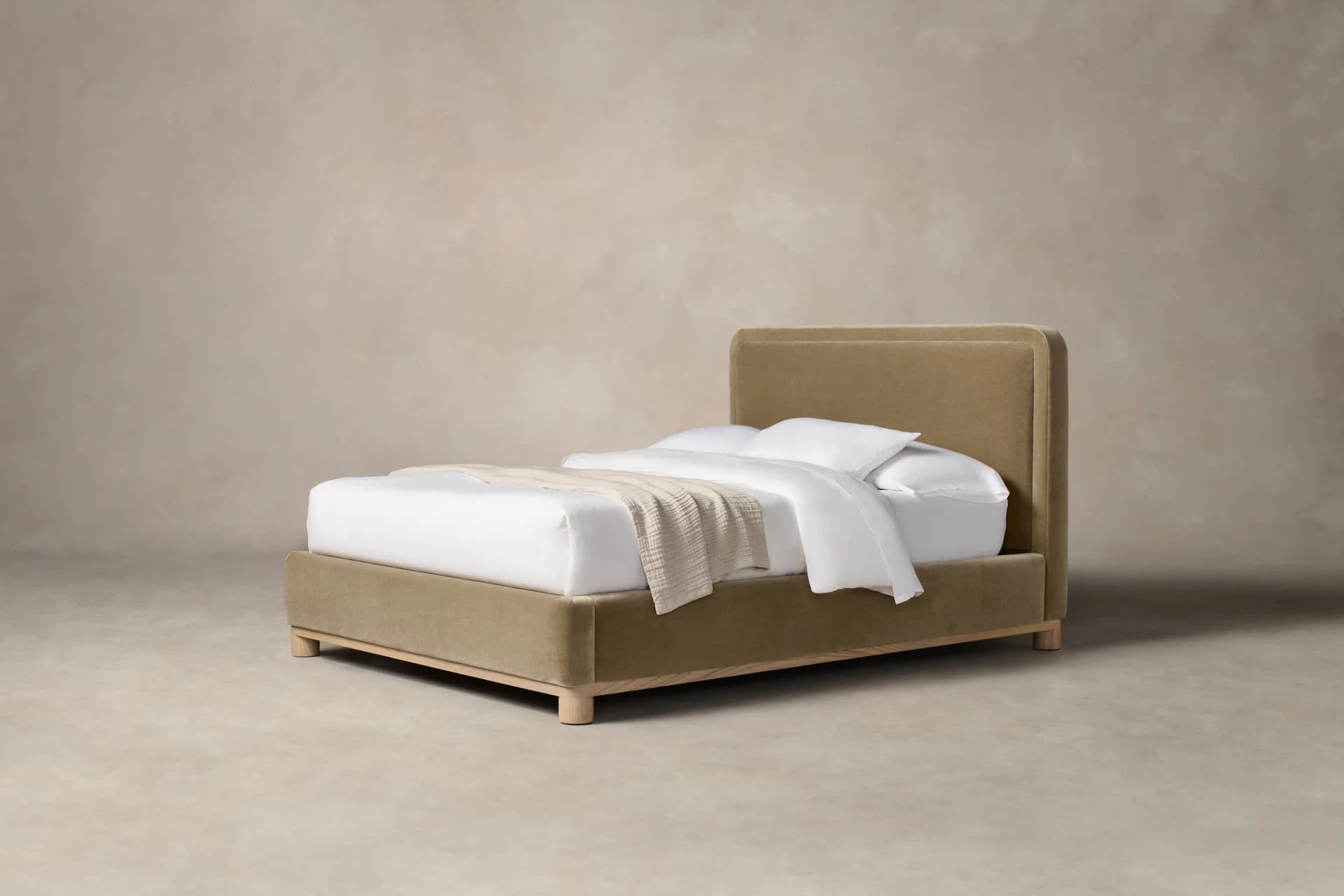 A modern upholstered bed frame with a rectangular headboard and a low-profile footboard. The frame is covered in a textured fabric, and it rests on short, cylindrical wooden legs. The bed is dressed with white linens and a textured throw blanket. — 3D model