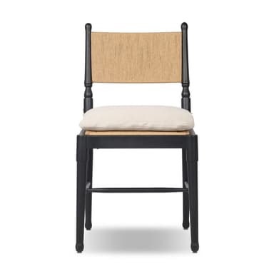 A contemporary dining chair featuring a solid black wooden frame, a natural woven rattan backrest, and a light beige fabric cushion positioned on a cane seat. The chair incorporates turned elements on its back posts and subtly tapered legs. — 3D model