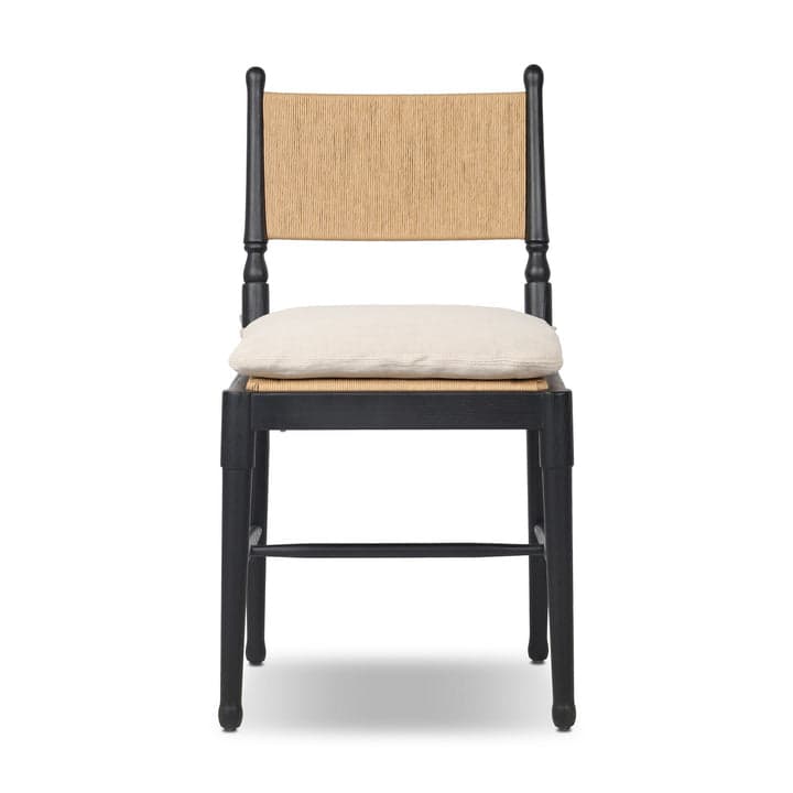 A contemporary dining chair featuring a solid black wooden frame, a natural woven rattan backrest, and a light beige fabric cushion positioned on a cane seat. The chair incorporates turned elements on its back posts and subtly tapered legs. — 3D model