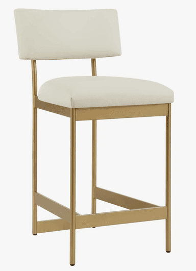 A modern bar stool featuring a gold-finished metal frame with a rectangular footrest and four legs. The seat and backrest are upholstered in a light, off-white or cream fabric/leatherette. The backrest is gently curved, and the frame extends up to support it. The overall design is sleek and contemporary. — 3D model