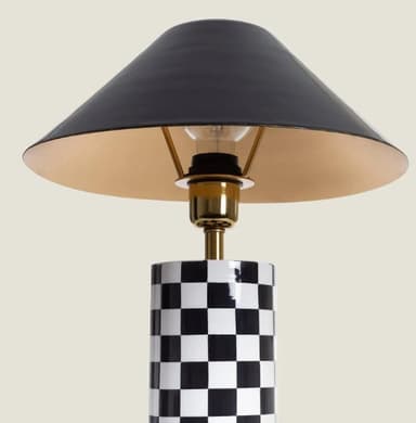 A contemporary table lamp featuring a cylindrical base adorned with a black and white checkerboard pattern, a brass-finished stem, and a glossy black conical shade. — 3D model