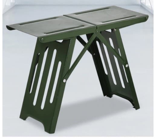 A portable, foldable stool with a matte dark green finish. The stool features a rectangular seat composed of two joined panels. The legs are constructed from folded sheet metal, forming an 'X' shape when viewed from the side, with decorative and weight-reducing vertical cutouts. The stool appears to be made of metal and is designed for outdoor or utility use. — 3D model