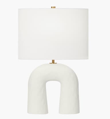 A modern table lamp featuring a distinctive arch-shaped ceramic base and a classic cylindrical fabric drum shade. — 3D model