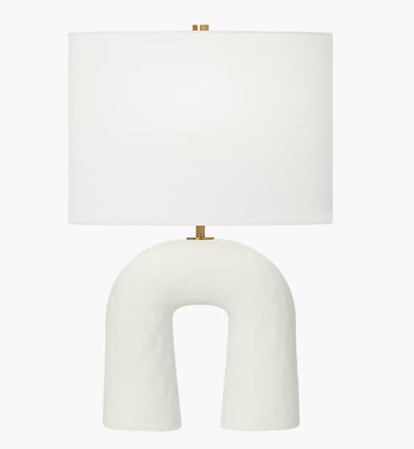 A modern table lamp featuring a distinctive arch-shaped ceramic base and a classic cylindrical fabric drum shade. — 3D model