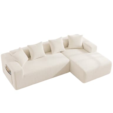 A modern, cream-colored sectional sofa featuring a chaise lounge component and an integrated storage pocket on one armrest. The sofa is upholstered in a textured fabric, likely boucle, providing a soft and inviting appearance. It has a low-profile, modular design with clean lines and includes several loose back cushions of the same material. — 3D model