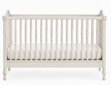 A light-colored, traditional style wooden crib featuring turned spindles and paneled end posts. The finish appears distressed or washed, giving it a soft, aged aesthetic. A white mattress is visible inside. — 3D model