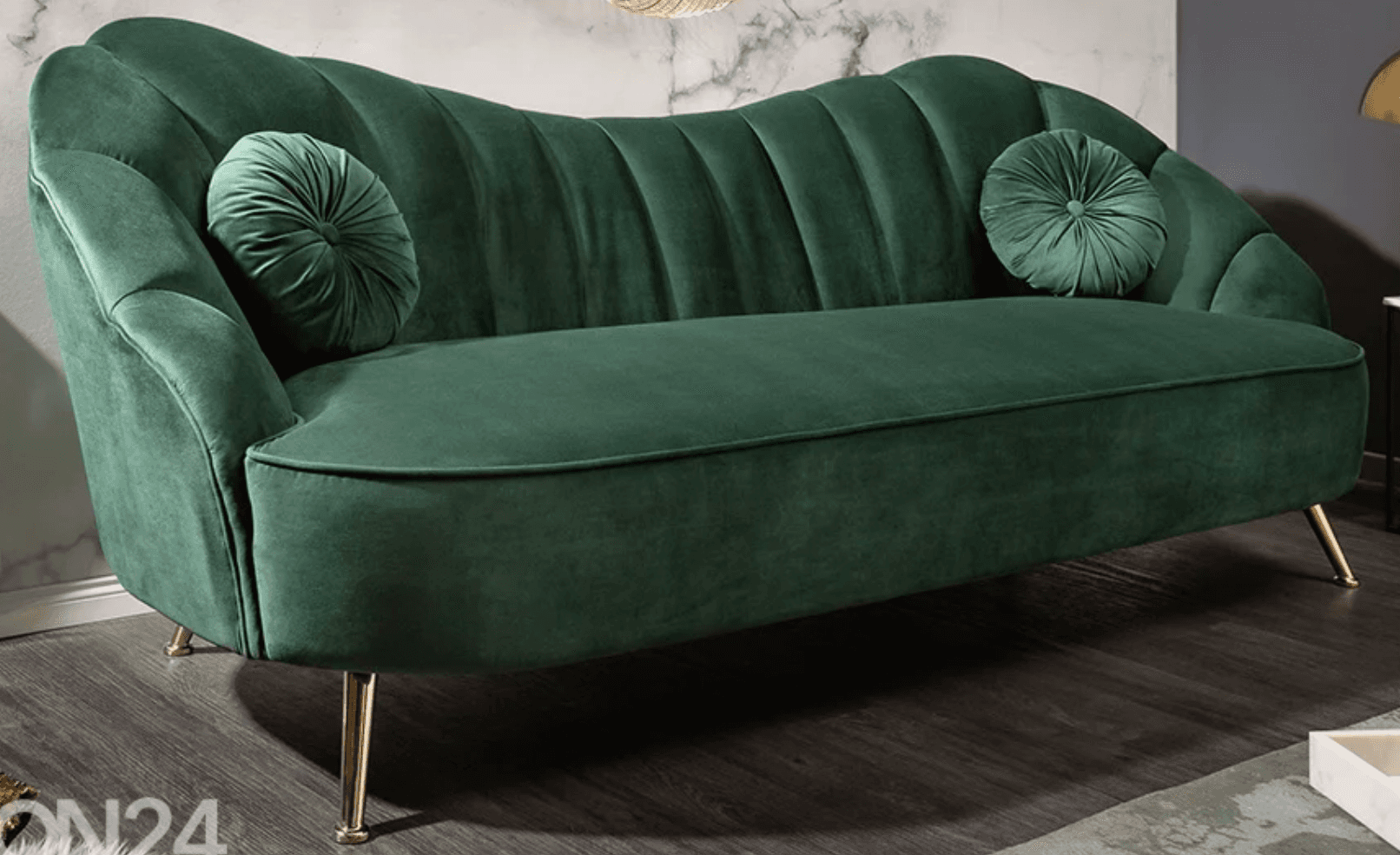 A dark green velvet sofa with a sculpted, fluted backrest and curved armrests. It features two round, tufted throw pillows. The sofa is supported by four slender, angled legs with a brass finish. — 3D model