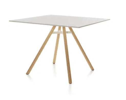 A modern square dining table featuring a white tabletop and splayed natural wood legs, connected by a white central support structure. — 3D model