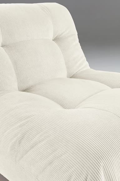 A low-profile armchair upholstered in cream-colored corduroy fabric. The armchair features a tufted backrest and seat, with plush, rounded armrests that seamlessly integrate into the base. The corduroy material exhibits distinct vertical ribbing, contributing to its textured appearance. The overall design is modular and contemporary, emphasizing comfort and a relaxed aesthetic. — 3D model